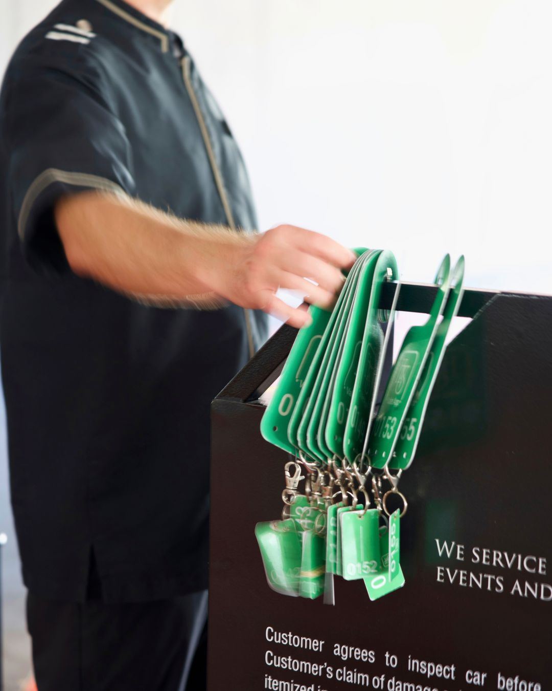 Attendant in a black HVS uniform with numbered valet key tags