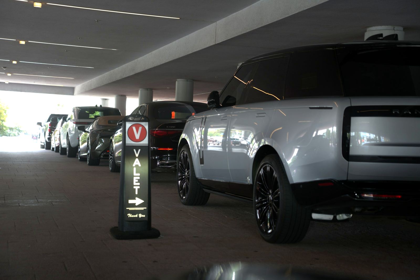 Valet sign and vehicles lined up at a covered entrance